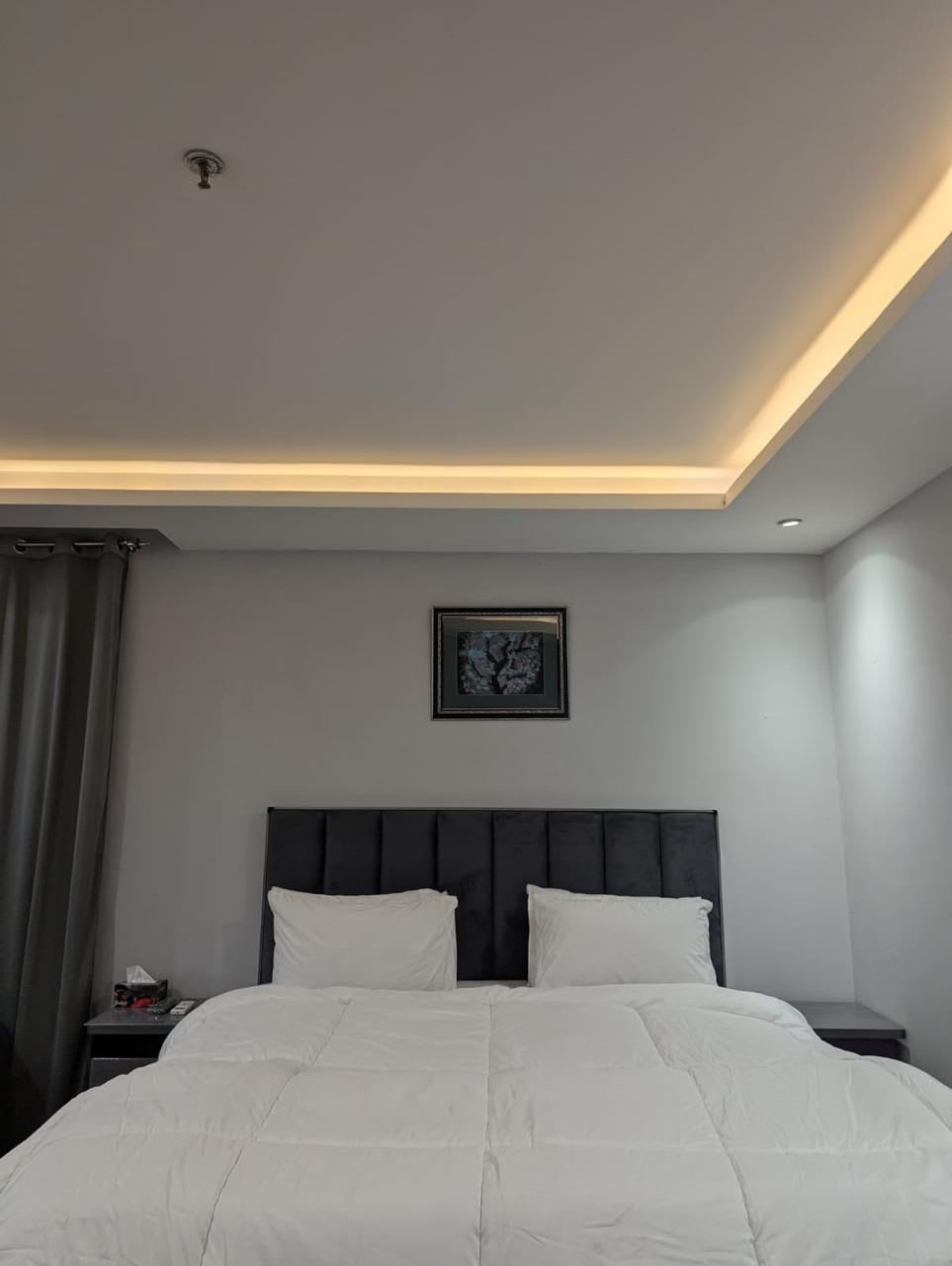 Studio bed with a dark upholstered headboard and white bedding
