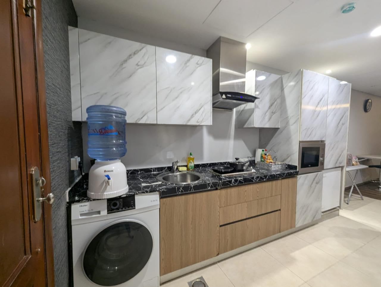 Kitchen with a washer, microwave and wood-toned lower cabinets