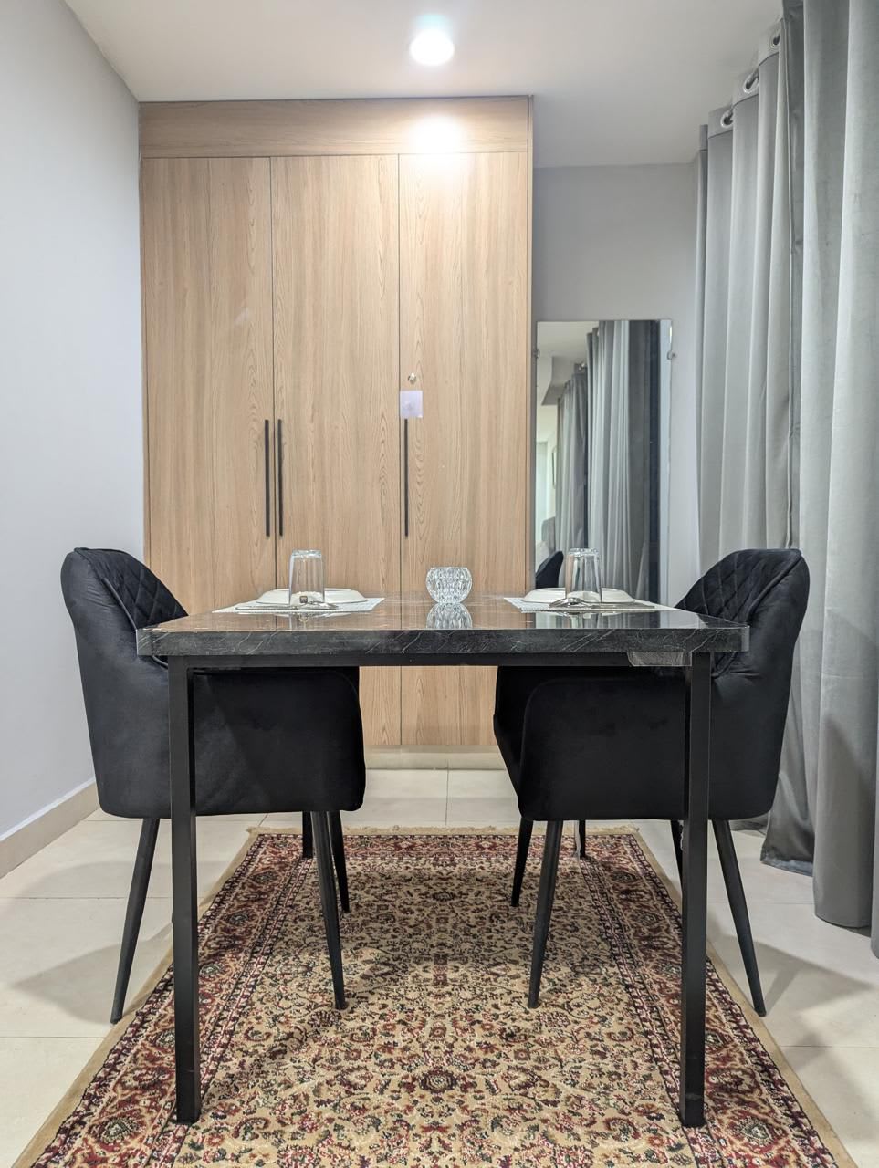 Glass dining table with four chairs beside the wardrobe
