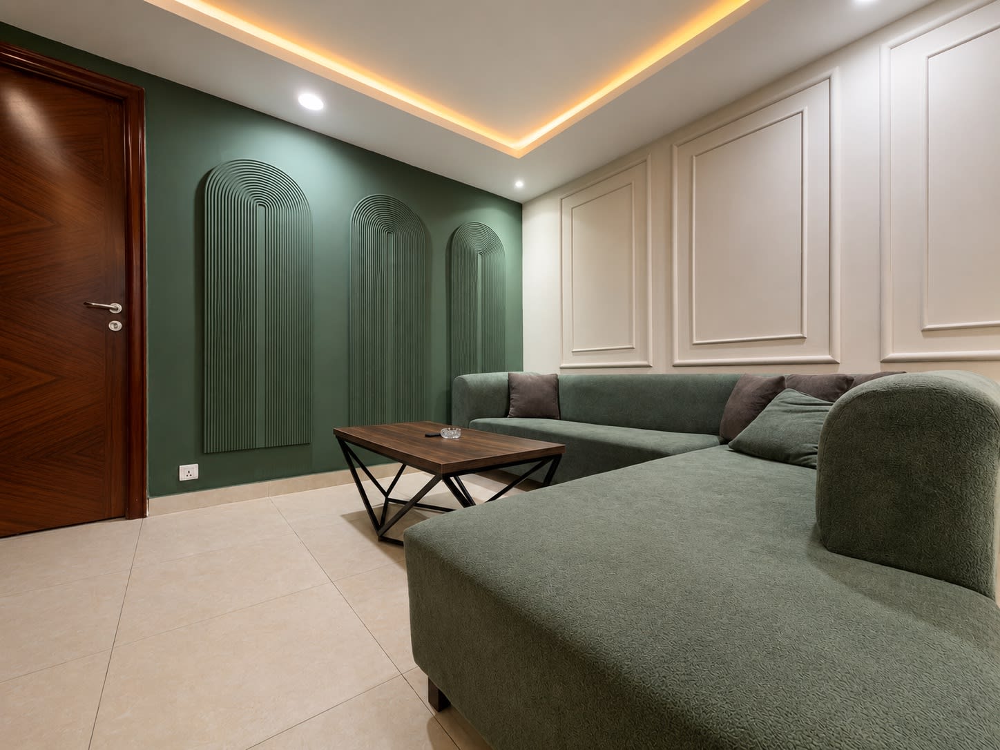 Green L-shaped sofa against the white panelled lounge wall