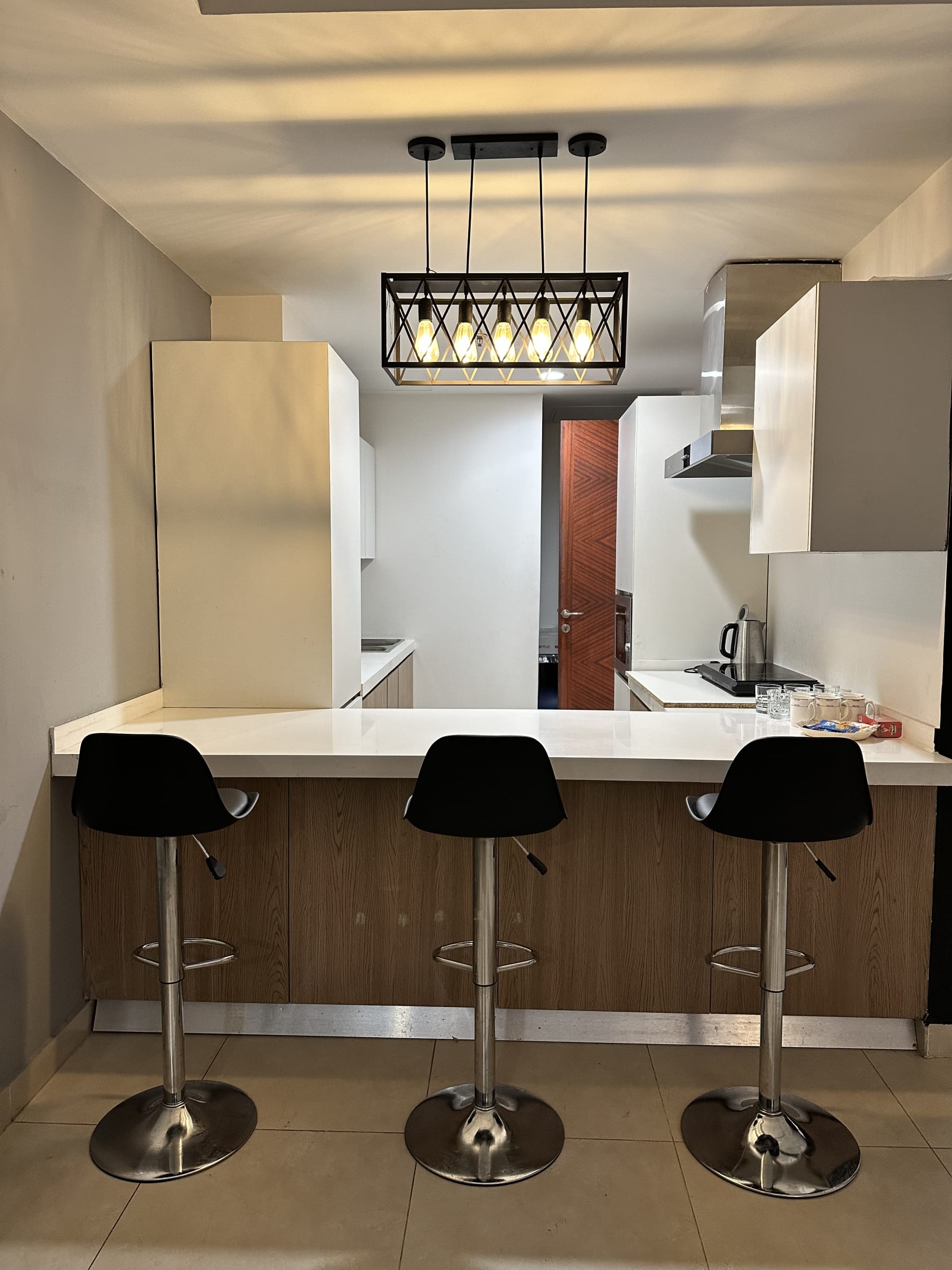 Breakfast bar with three black stools and a pendant light
