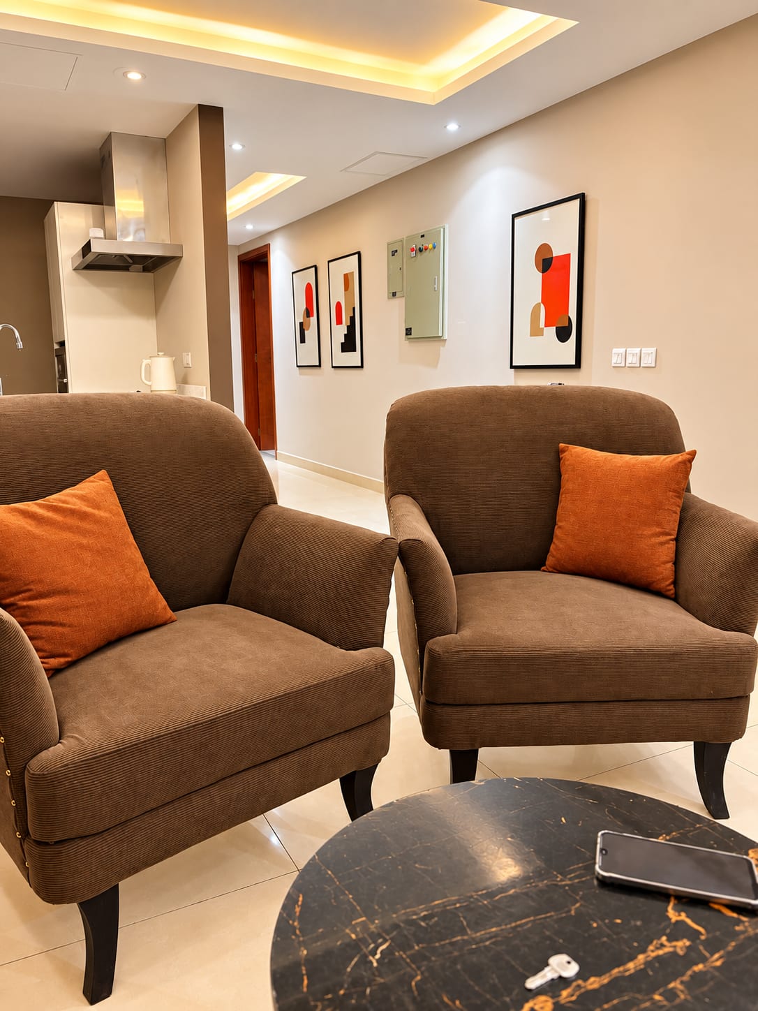 Two brown upholstered armchairs with orange cushions beside the lounge coffee table