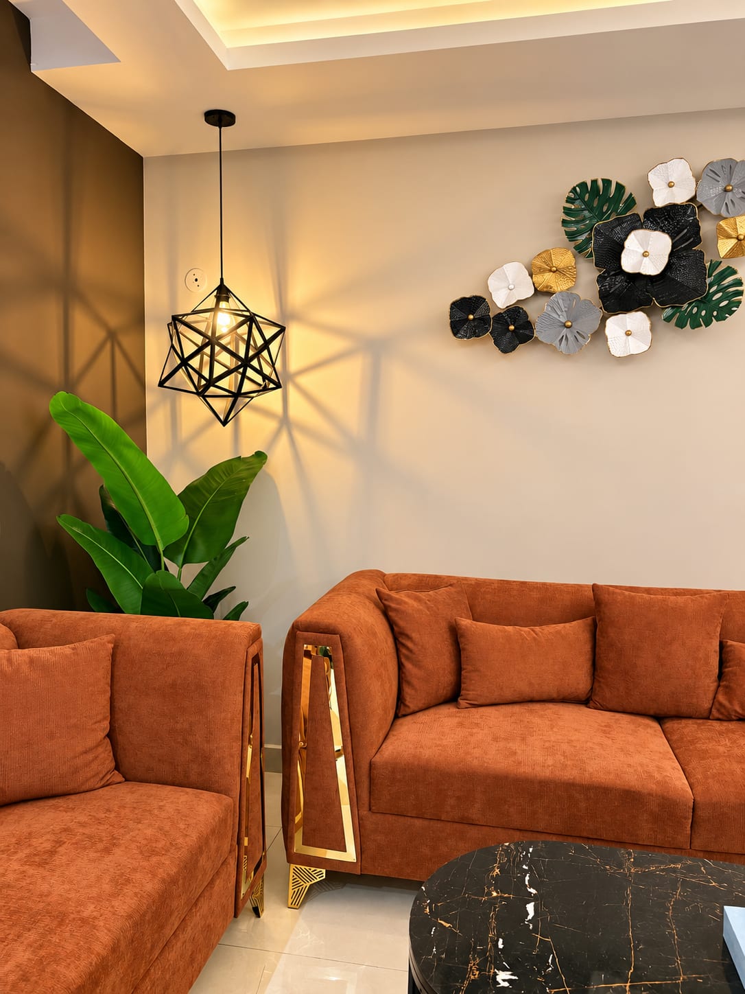 Lounge seating with rust-orange sofas, a geometric pendant light and decorative wall art