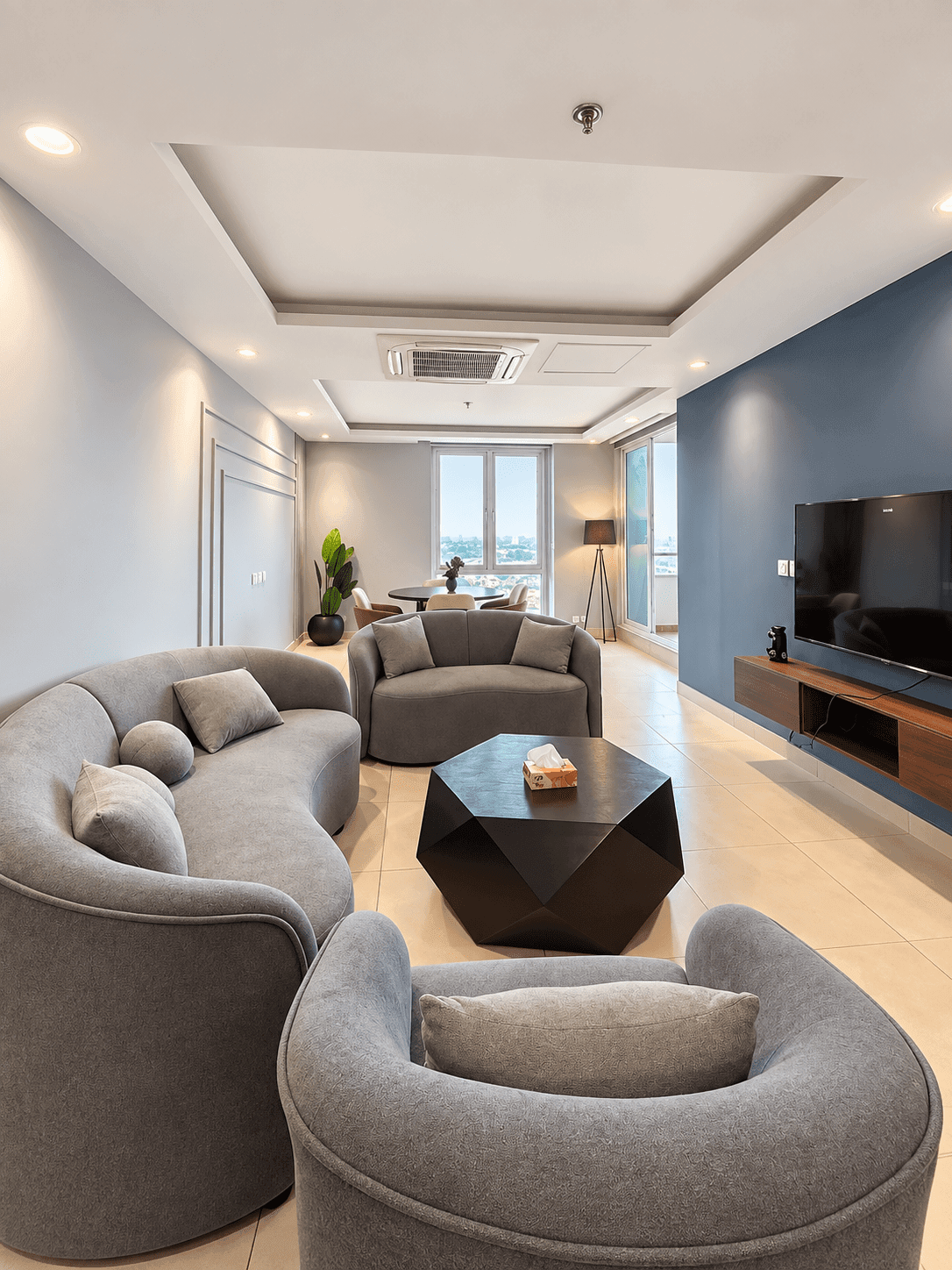 The Urban Nest living room with curved grey seating, a black coffee table and a blue TV wall