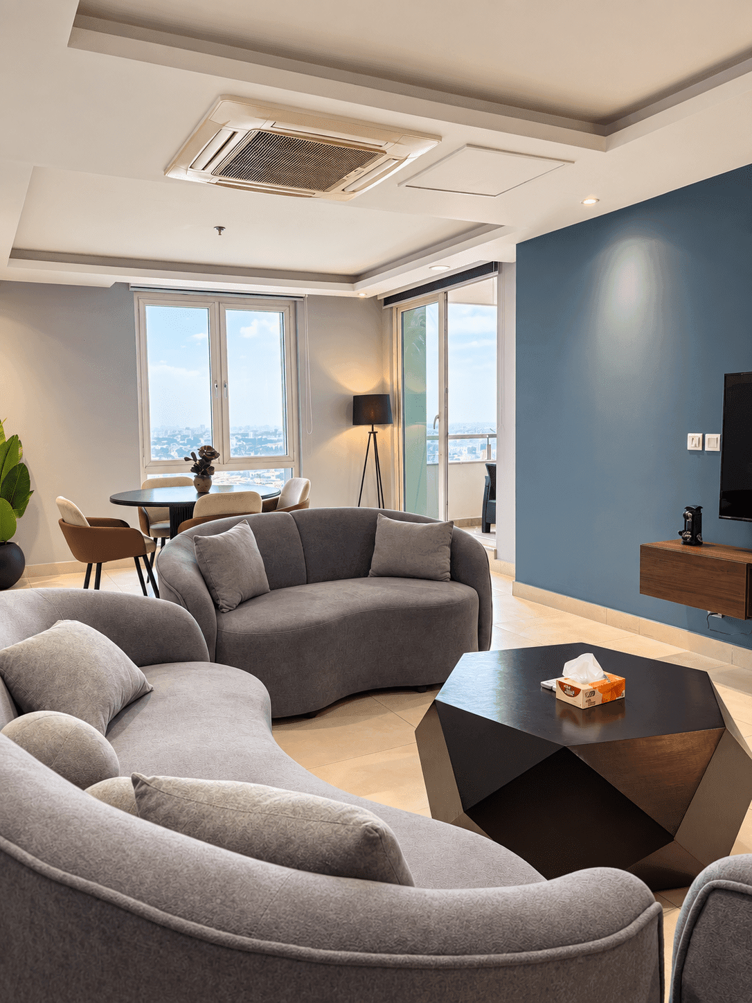Grey lounge seating beside the window-side dining area in The Urban Nest