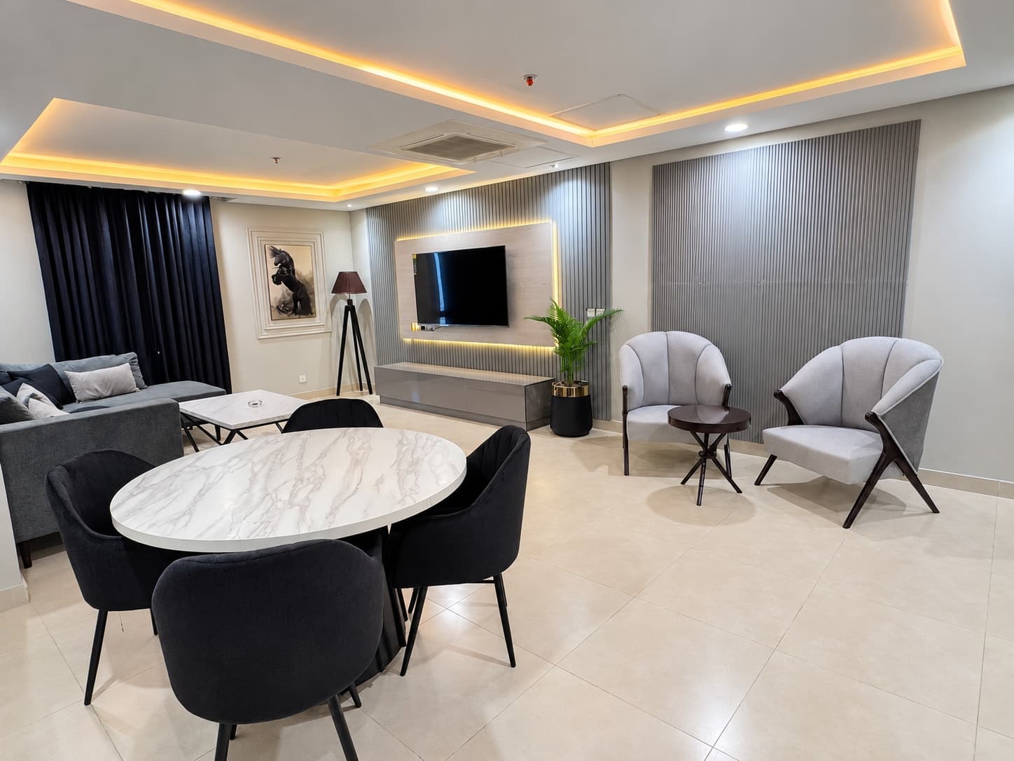 Round dining table with black chairs beside two grey accent chairs and the open lounge