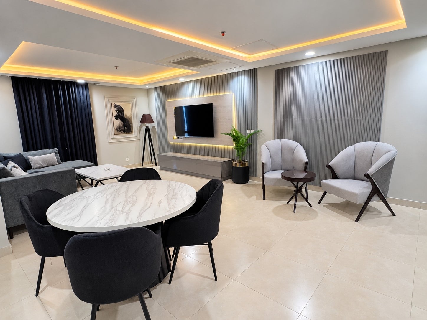 Round dining table with black chairs beside two grey accent chairs and the open lounge