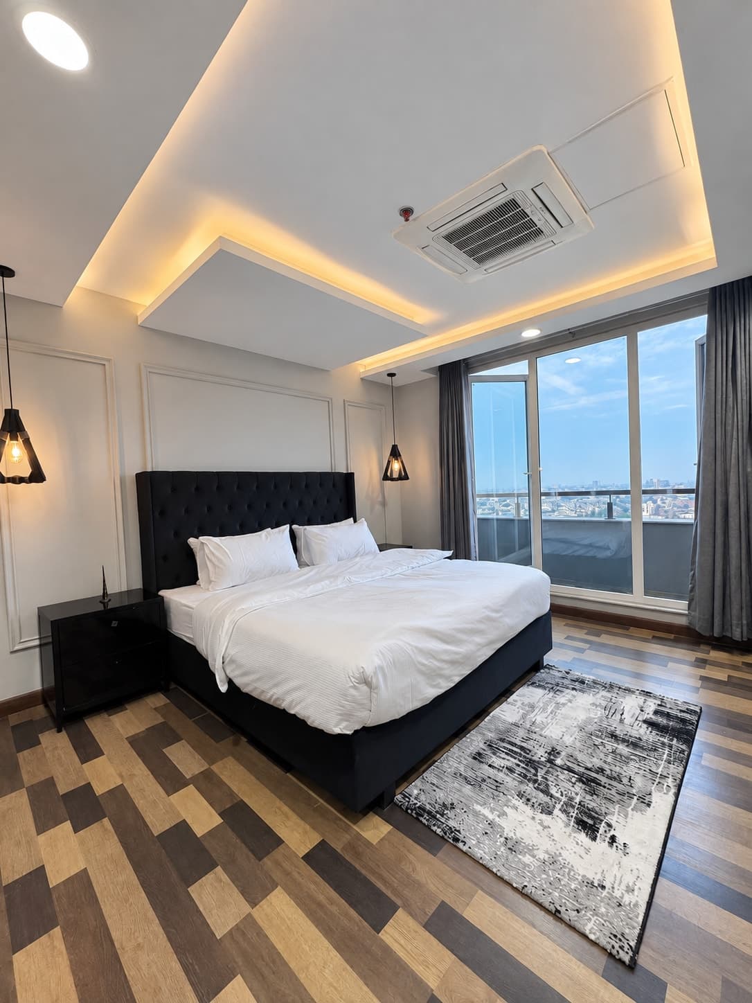 Bedroom with a dark upholstered bed, white linen and glass doors overlooking the balcony